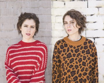 Tegan and Sara standing in front of a brick wall