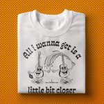 Folded "All i wanna get is a little bit closer" shirt design on orange background pattern.